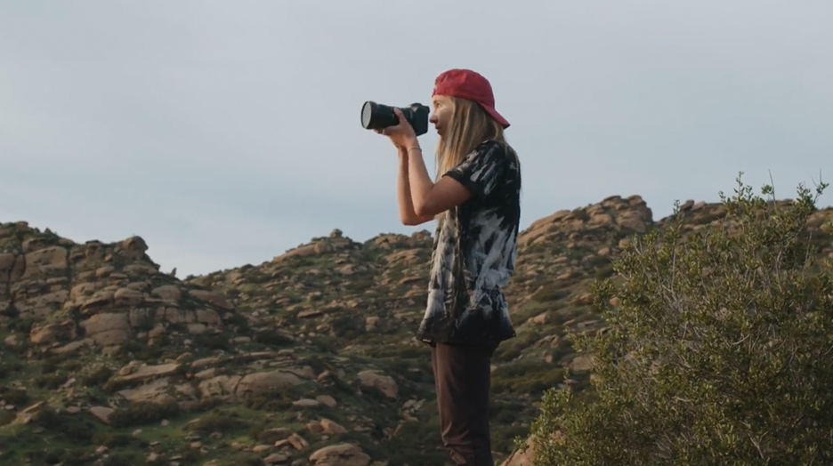 Heather Young standing taking a photo with her camera