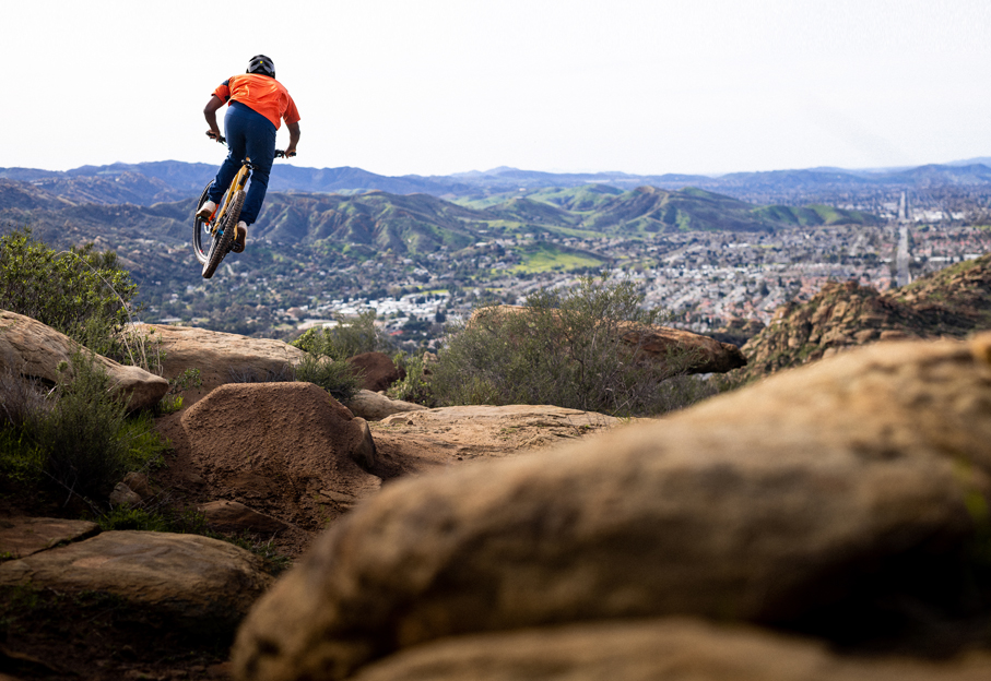 Shimano athlete Elliot Jackson hitting a jump on his mountain bike 