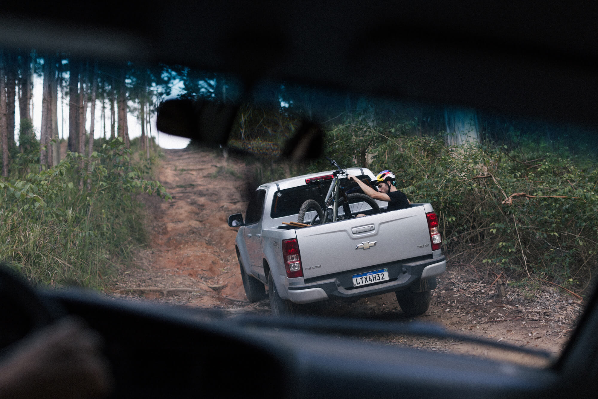 Henrique riding in the back of a truck to the top of the trail 