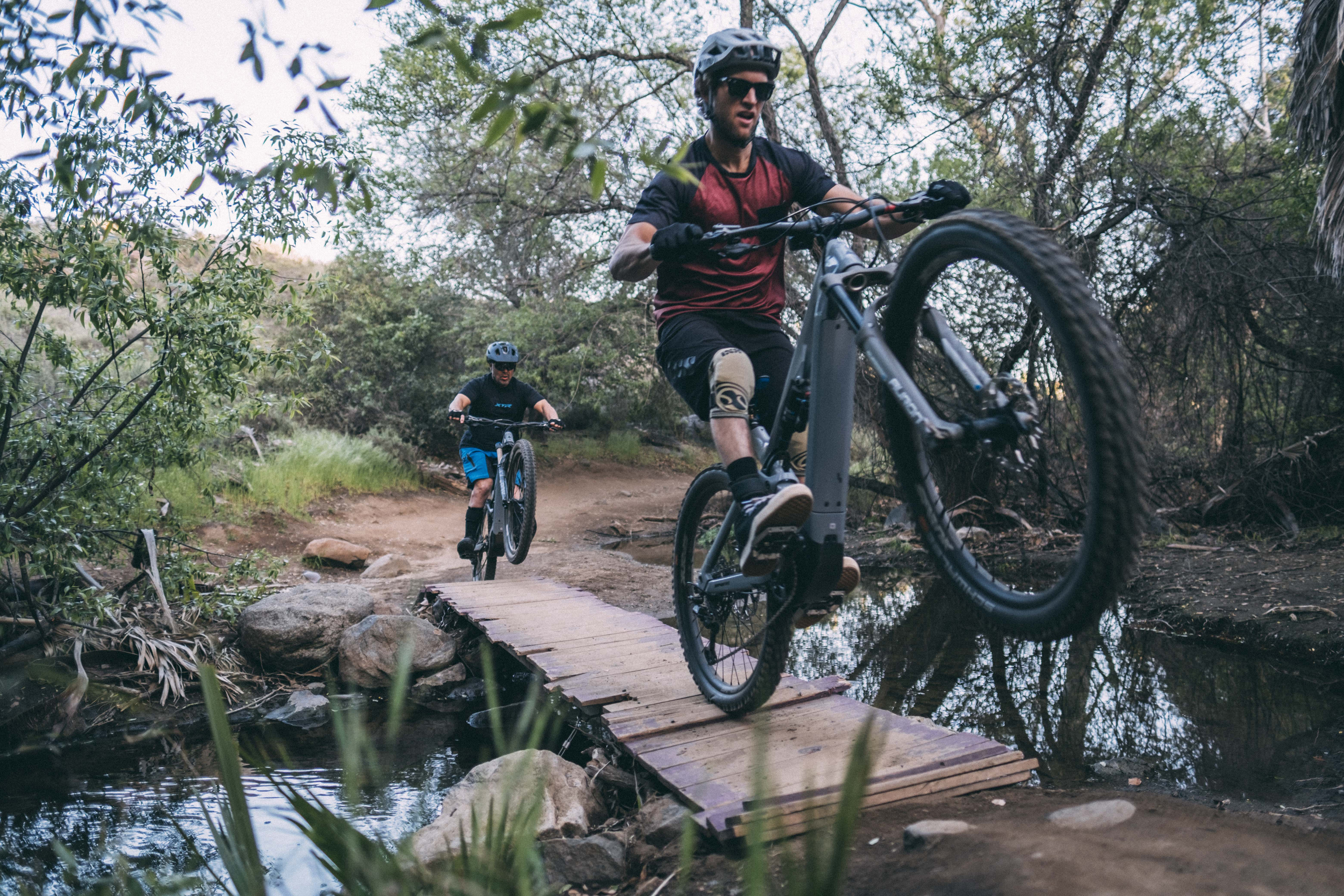 doing a wheelie on an emtb over a creek